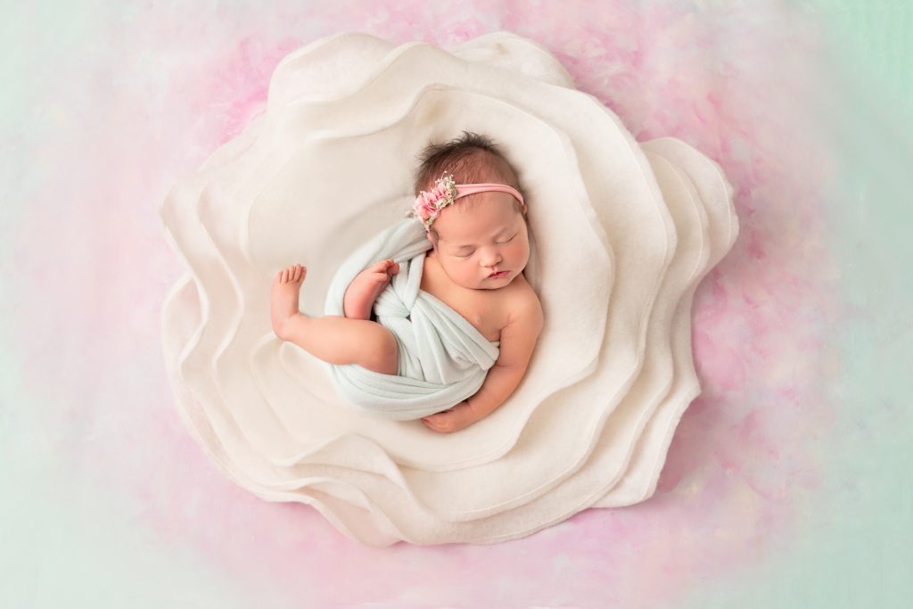 Newborn Baby Girl in a flower on a mint and pink Hand Painted backdrop by Horsham Photographer 